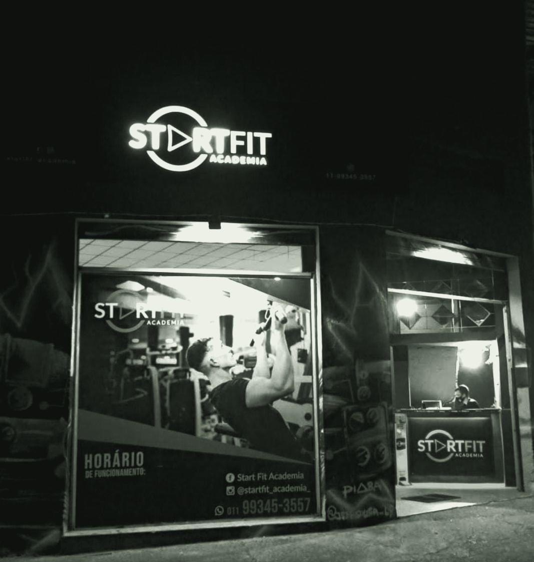 Fachada da StartFit Academia à noite, com o letreiro iluminado