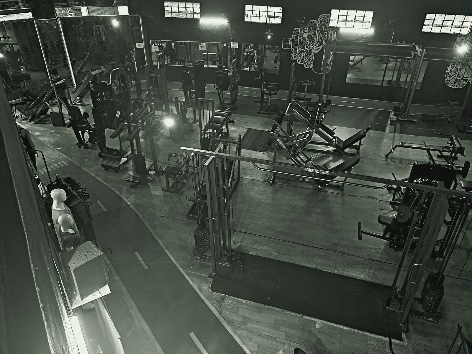 Vista do alto do salão de musculação da StartFit, com aparelhos e a pista de corrida vermelha